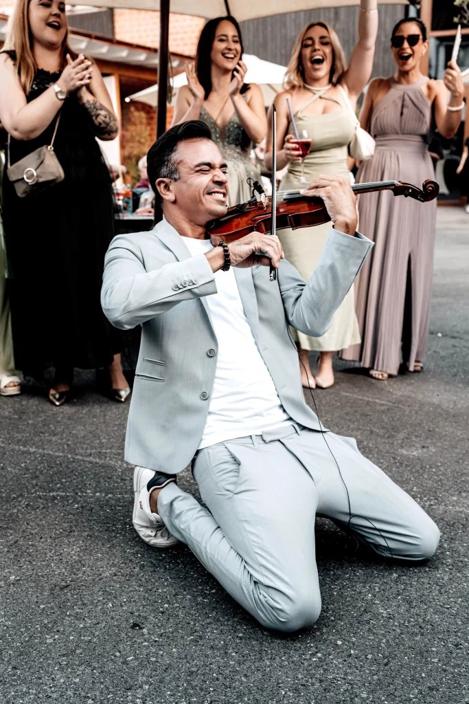 Martin Guha spielt Violine zum Sektempfang nach der Trauung. Das Publikum feiert.